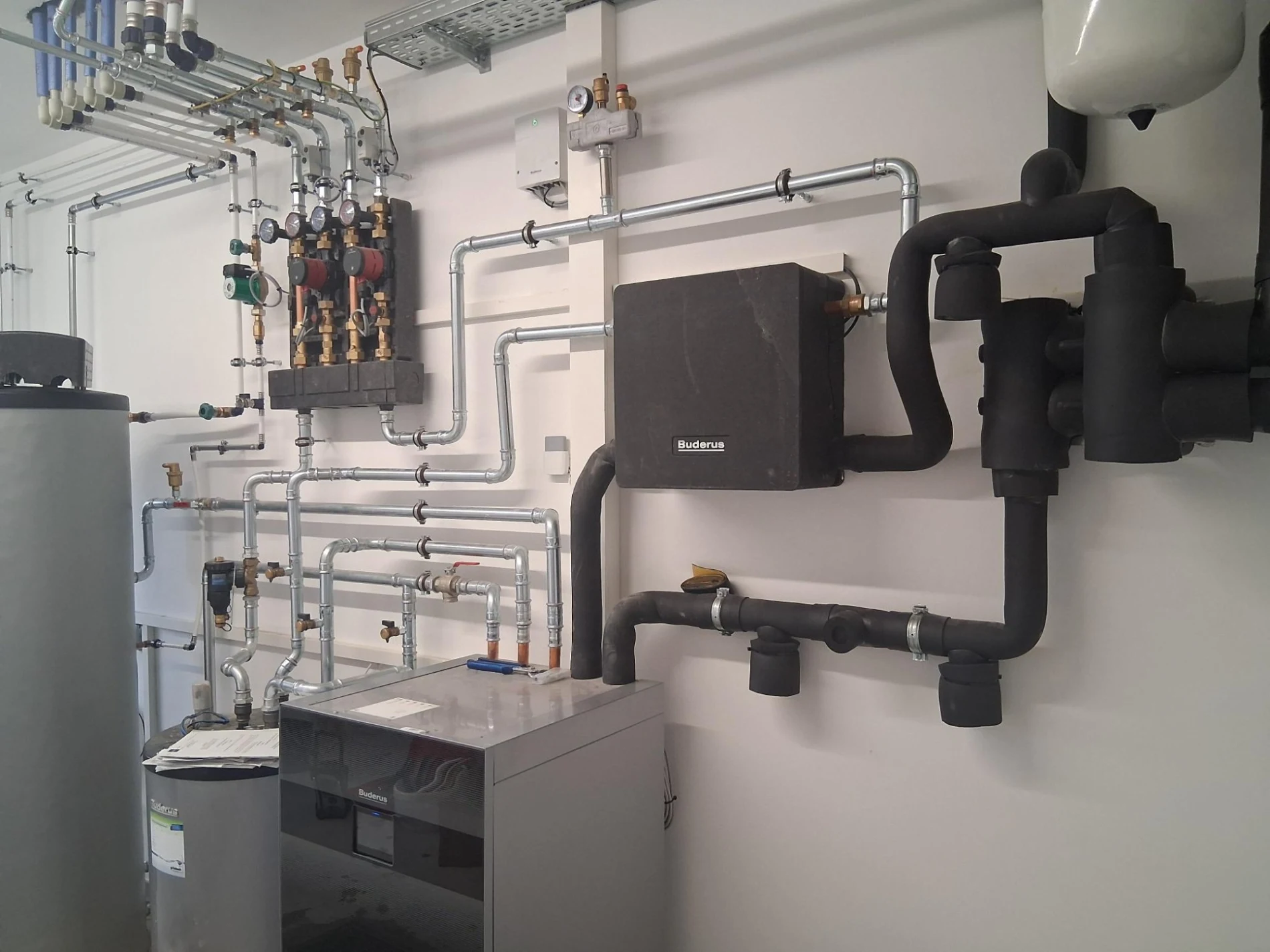 Heizraum mit Verteiler, Pumpengruppen und Speicher - Heizungsinstallation von HWS