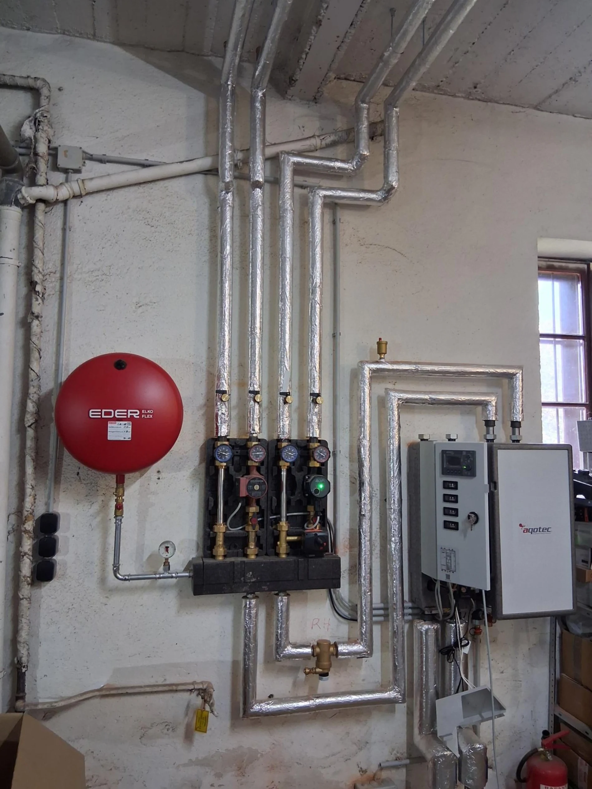 Technikraum mit Ausdehnungsgefaess, Pumpengruppen und Waermeverteilung